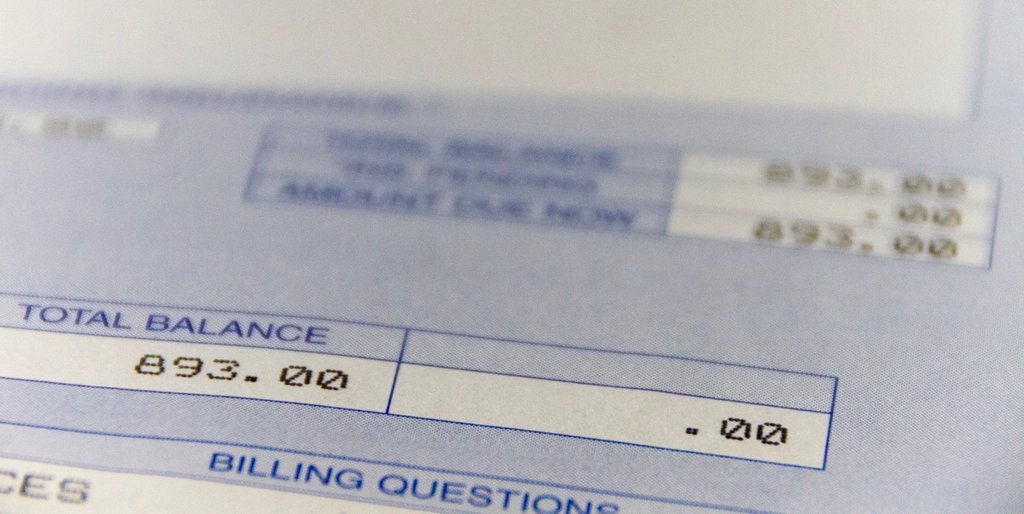 Close-up of a paper billing statement showing a total balance and a Billing Questions section