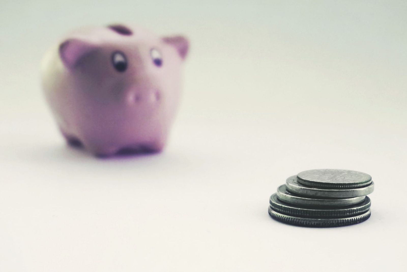 A small piggy bank beside a stack of coins
